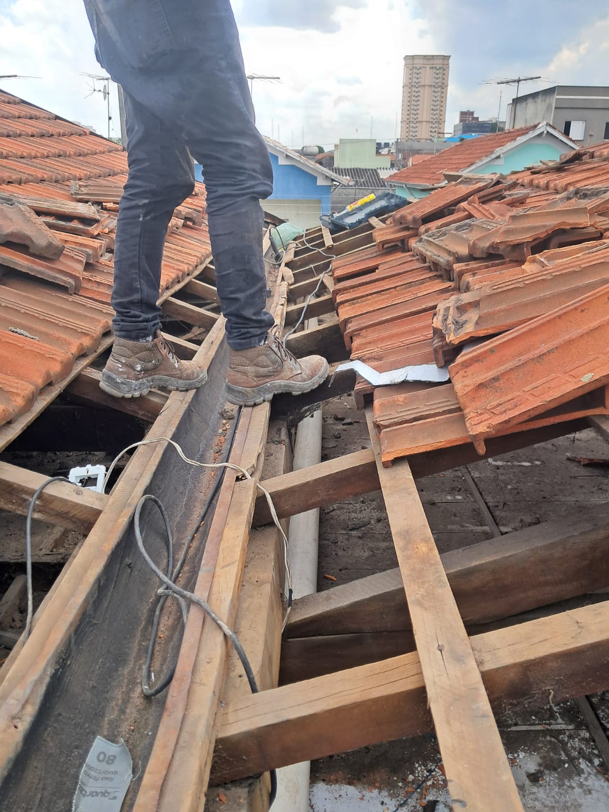 Profissional em cima do telhado trabalhando em estrutura de calhas e telhas
